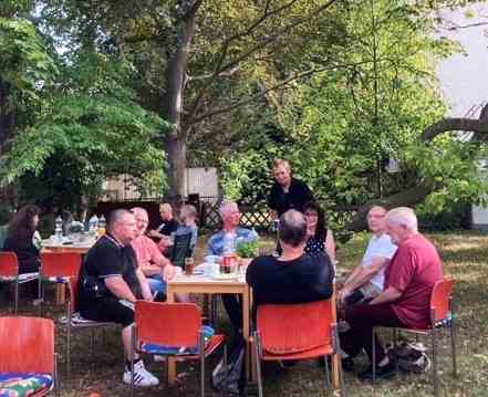Menschen sitzen an Gartentisch - Ehemaligentreffen der Fachambulanz Peine