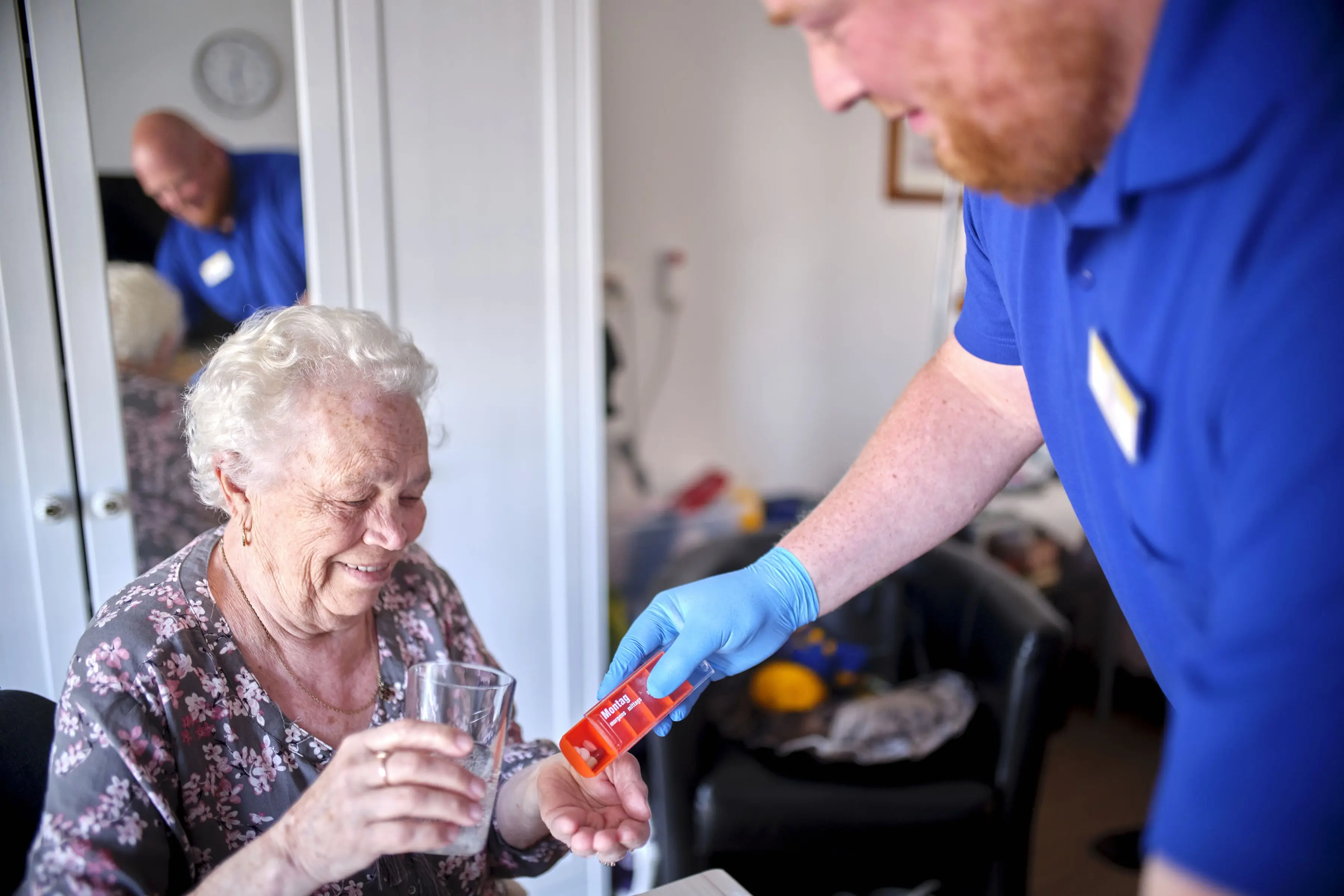 Eine Pflegekraft versorgt eine Seniorin.