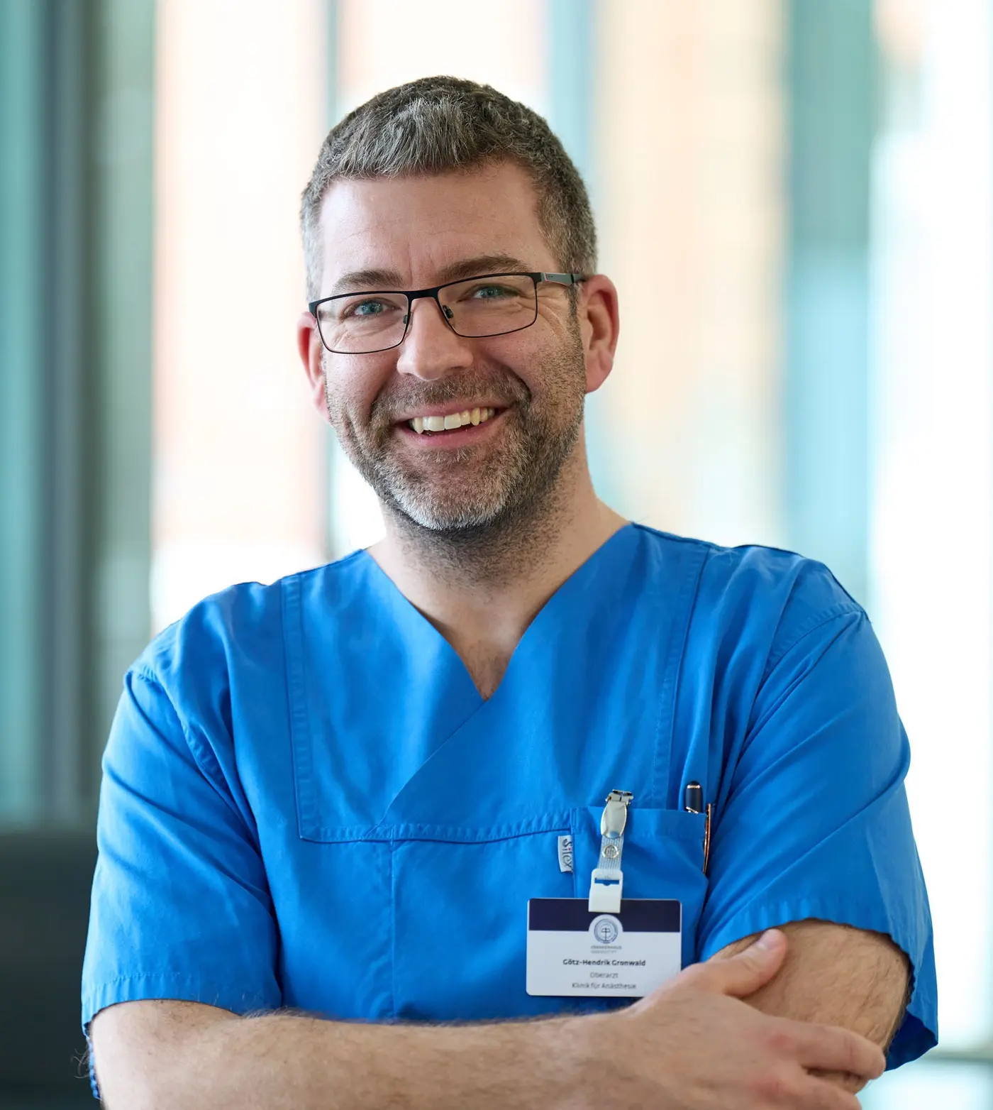 Götz-Hendrik Gronwald im blauen Kasack. Im Hintergrund eine unscharfe Fensterfront