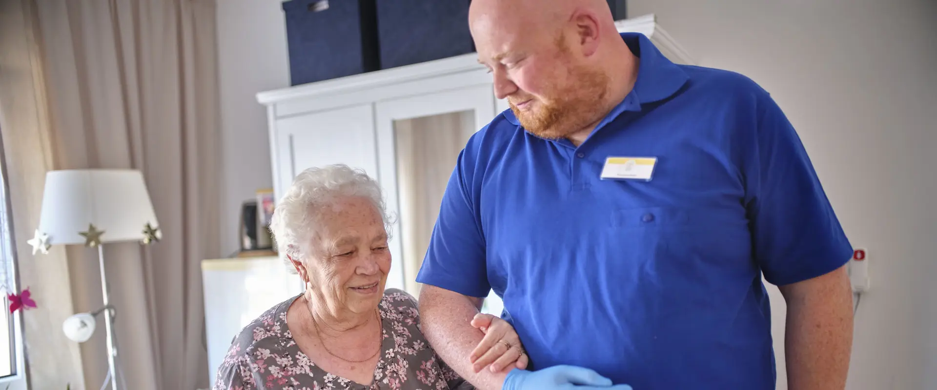 Ein Mitarbeiter der DHH unterstützt eine Seniorin.