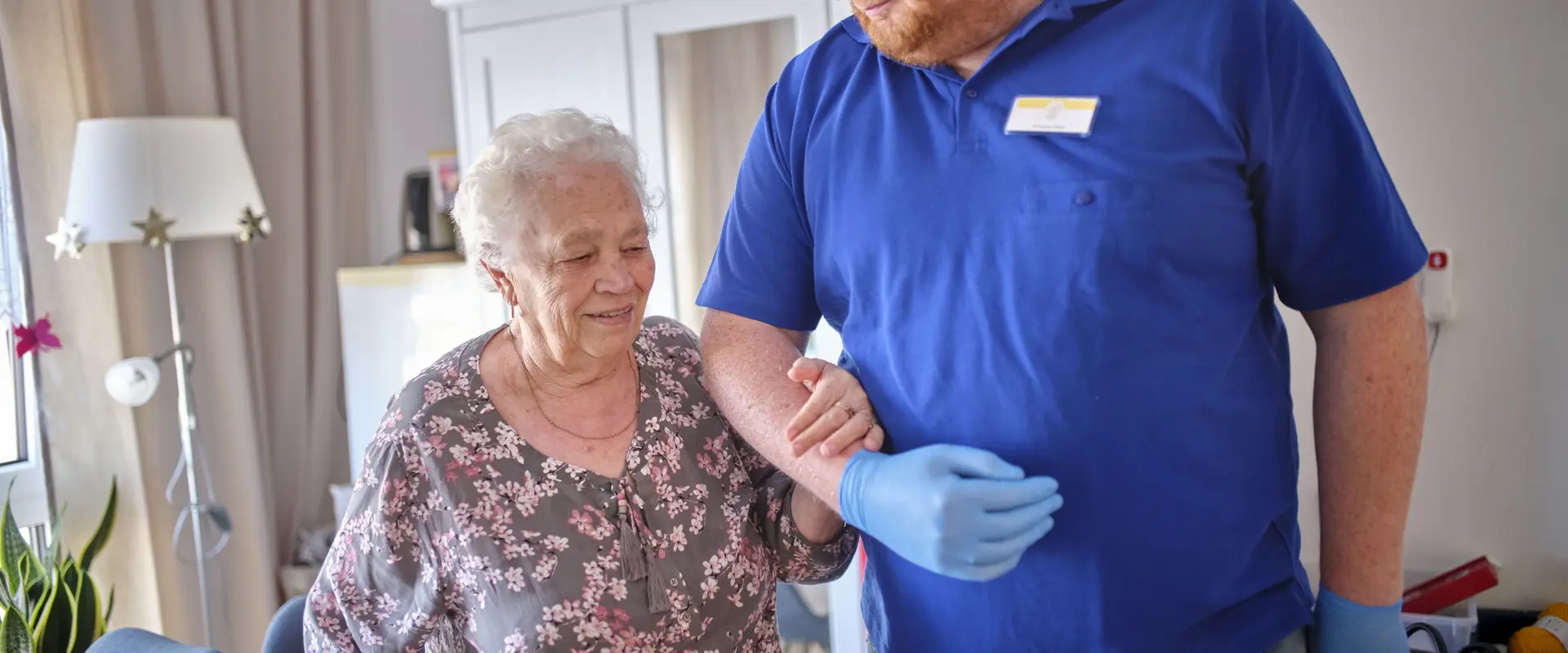 Ein Mitarbeiter der DHH unterstützt eine Seniorin.