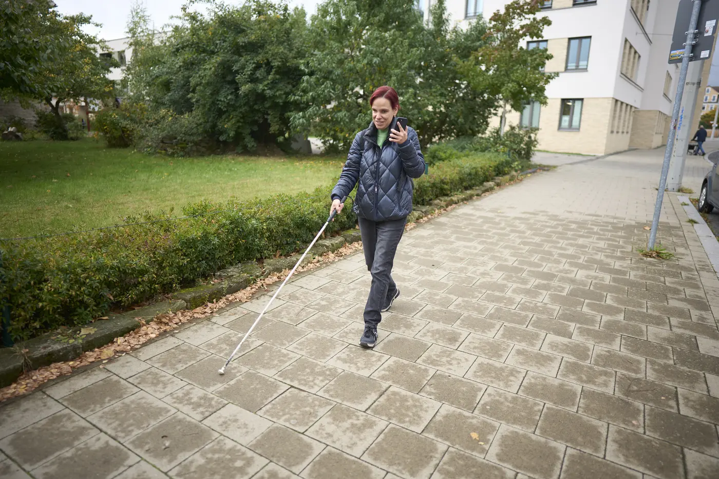 Frau geht mit weißen Langstock (Blindenstock) spazieren 