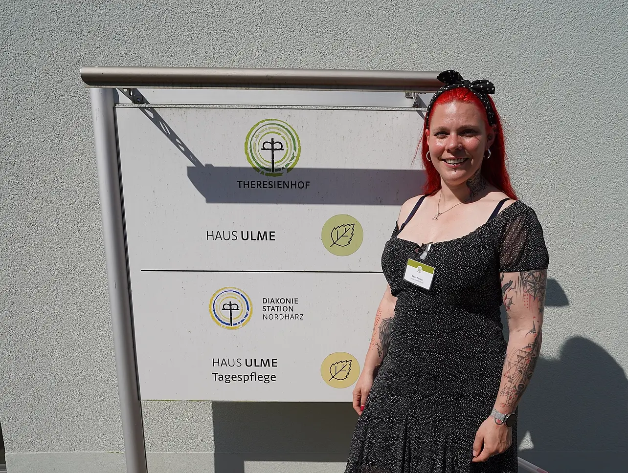 Sarah Zimmer steht vor einem Schild des Theresienhofs.