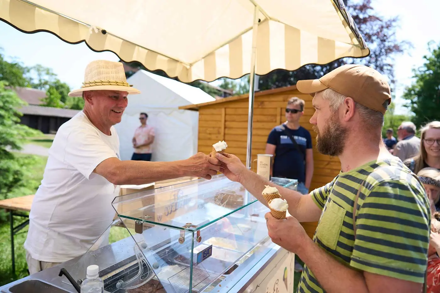 Mann am Eiswagen übergibt Eiswaffel an Kunden