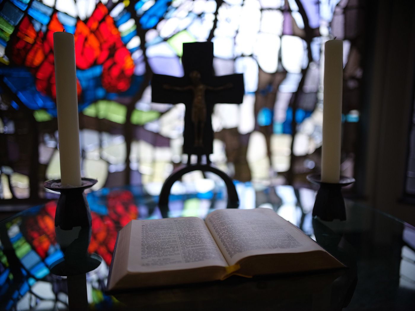 Bibel vor Kirchenfenster mit Kreuz im Hintergrund