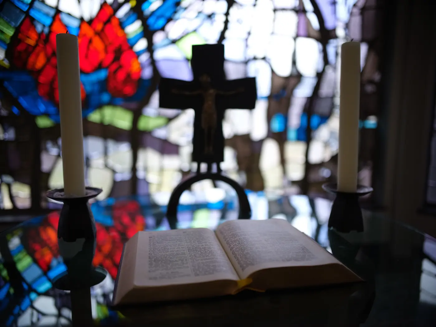 Bibel vor Kirchenfenster mit Kreuz im Hintergrund
