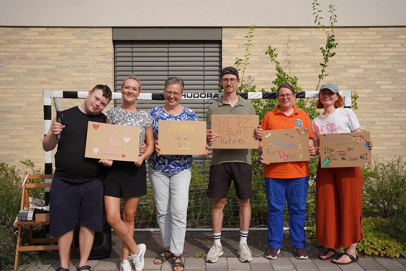 Das Bild zeigt die Menschen mit ihren Plakaten, die sie für den CSD Braunschweig gestaltet haben.