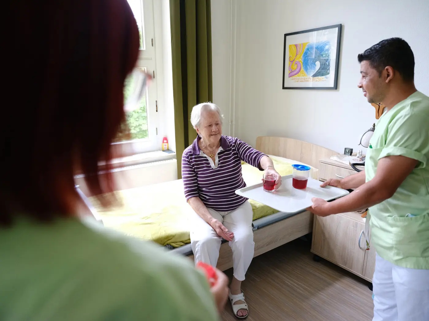 Seniorin mit Pflegekräften im Zimmer