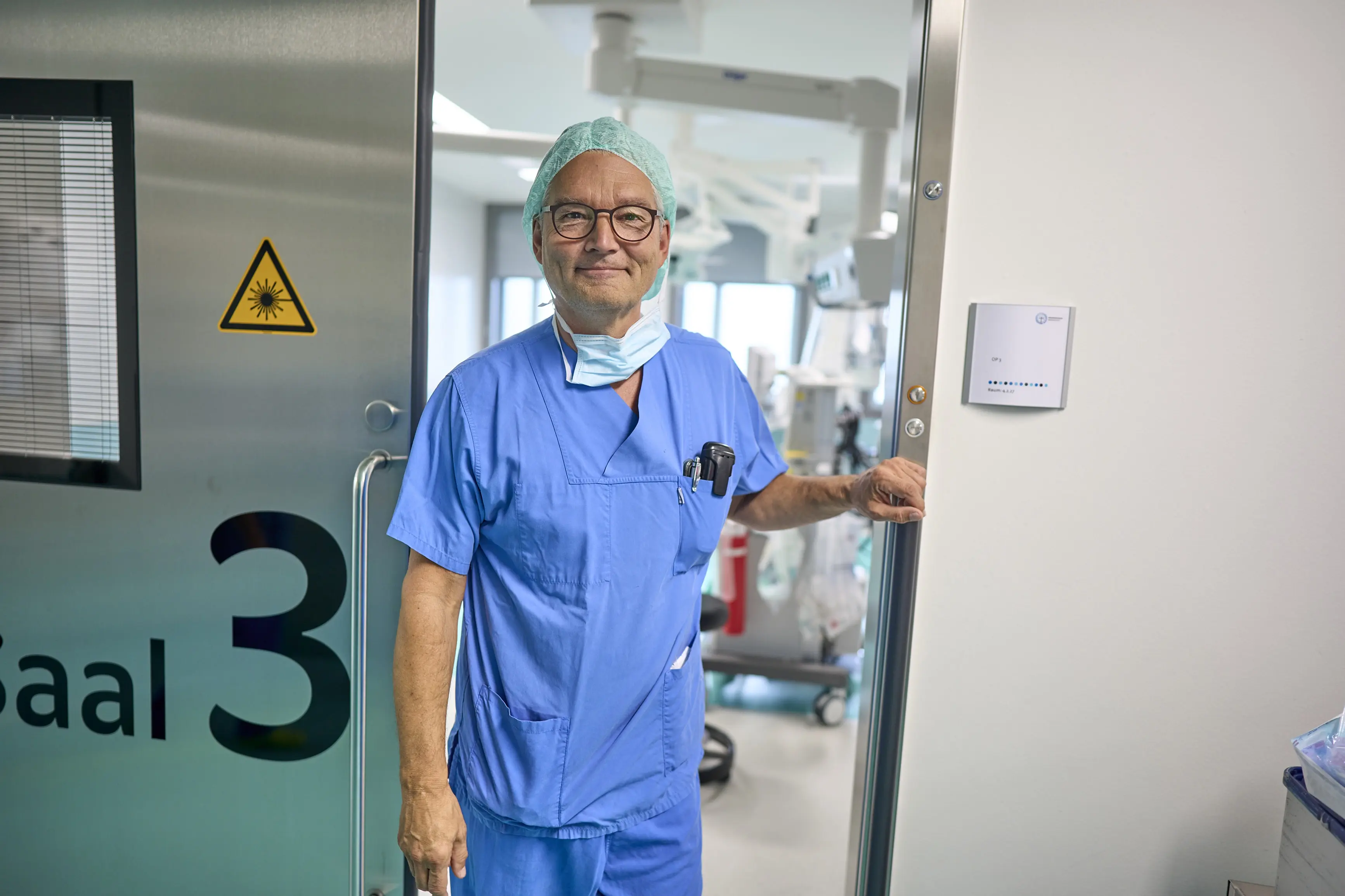 OP Manager Lotse in blauem OP Kasak vor dem OP Saal 