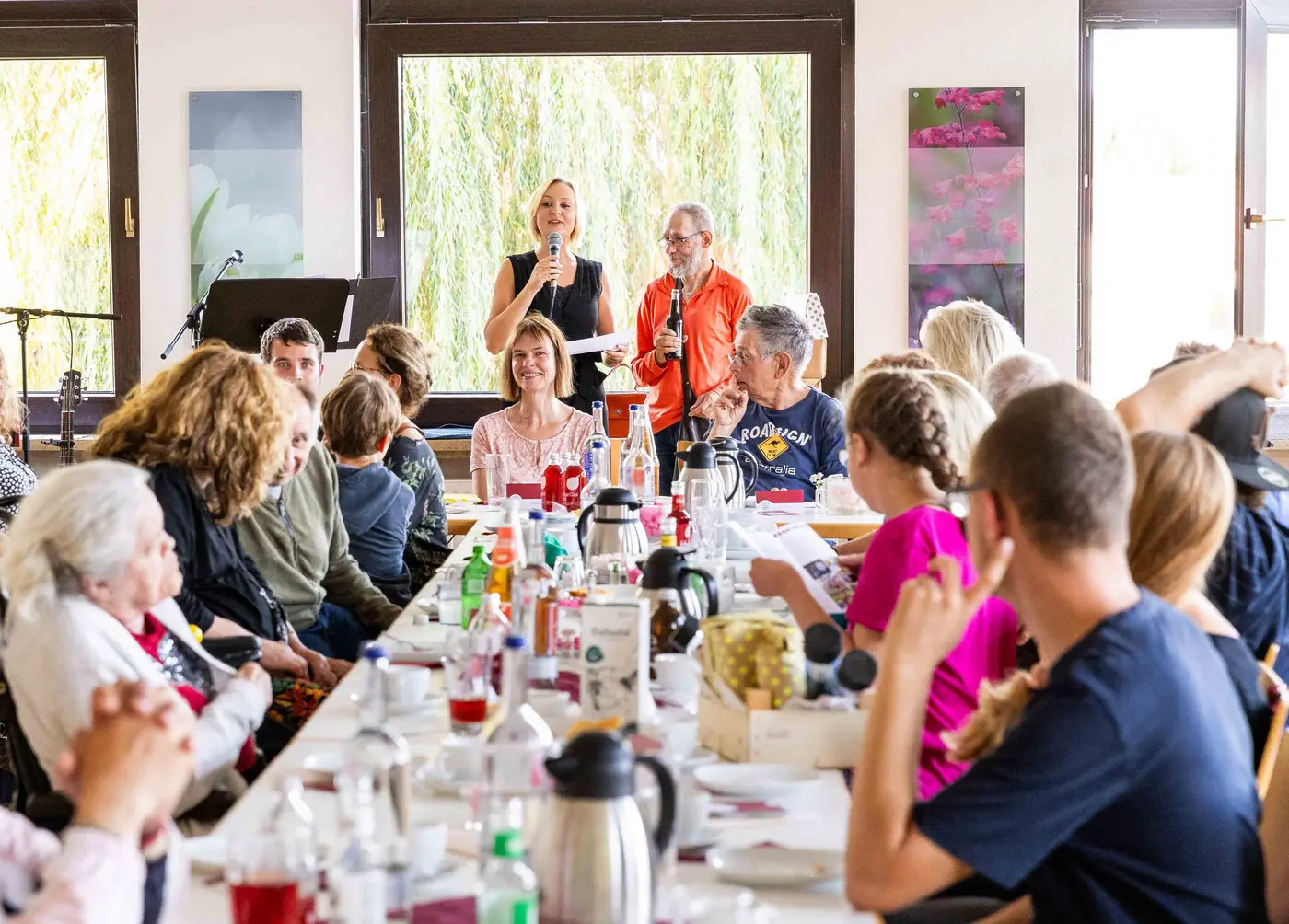 Gruppe Neuerkeröder Bürgerinnen und Bürger an einem großen Tisch bei Kaffee und Kuchen. Saskia Brauns erzählt etwas