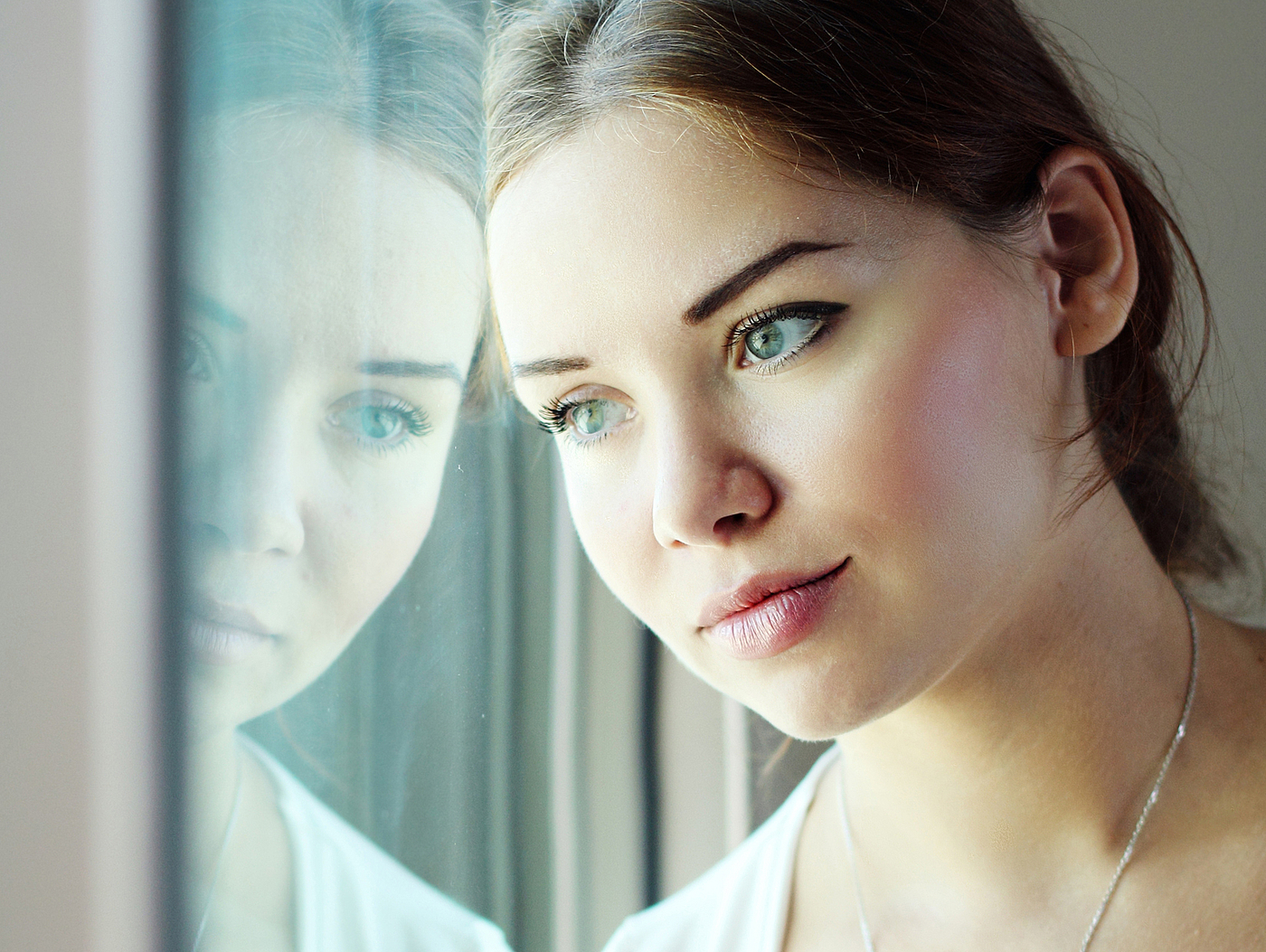 Junge Frau blickt melancholisch aus dem Fenster